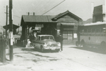 牛浜駅は昭和19年（1944）7月、旧陸軍の要請により、多摩飛行場（現在の横田基地）にあった航空審査部や熊川倉庫への通勤ために開設されました。写真は開設当初から昭和36年まで使われていた駅舎です。駅前に停車中の横文字のバスは米軍横田基地への送迎バスで、当時は基地へ通勤するための主要駅となっていました。