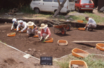 山根坂上遺跡は縄文時代中期の遺跡です。昭和46年に羽村町史編さん事業の一環として第一次調査が行われてから、第6次調査までが実施されていて、写真は第3次調査の作業風景を写したものです。これまでの調査の結果、直径150ｍ程の環状集落であることがわかり、羽村市指定文化財の釣手土器3点をはじめとした多数の遺物が発見されています。