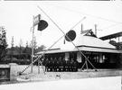 日野駅改築当時の駅員の記念写真。駅舎は、日野の農家をイメージして設計され、現在も使われている。<br />
写真左手の高所に「日野驛」の看板が設けられている。