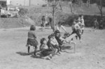 昭和40（1965）年3月に完成した東地区の児童公園について、その完成を告げた国立町報の記事に掲載された写真。<br />
手前では子ども達がシーソーで遊んでいますが、持ち上げられた3人の表情が何とも楽し気です。<br />
当時の町報によると、この公園の広さは2,500㎡、ブランコ・シーソー・ウンテイが各1台備え付けられオープンしたようです。<br />
この児童公園には「ぼんこ園」という愛称が地元の方々によって名づけられ、この愛称は現在まで受け継がれています。<br />
（「ぼんこ」とは、まだ種の落ちないような松ぼっくりを指した東北地方の言葉で、幼い子どもという意味もあるようです）
