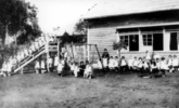 中央幼稚園（現・聖公会八王子幼稚園）は、明治45年（1912）米国宣教師夫人により開園した歴史ある幼稚園です。この写真は私立中央幼稚園の新築落成記念の絵葉書のうちの1枚で、運動場に設置されたブランコなどの遊具と子どもたちが写っています。（展示図録『セピア色の風景』に掲載）